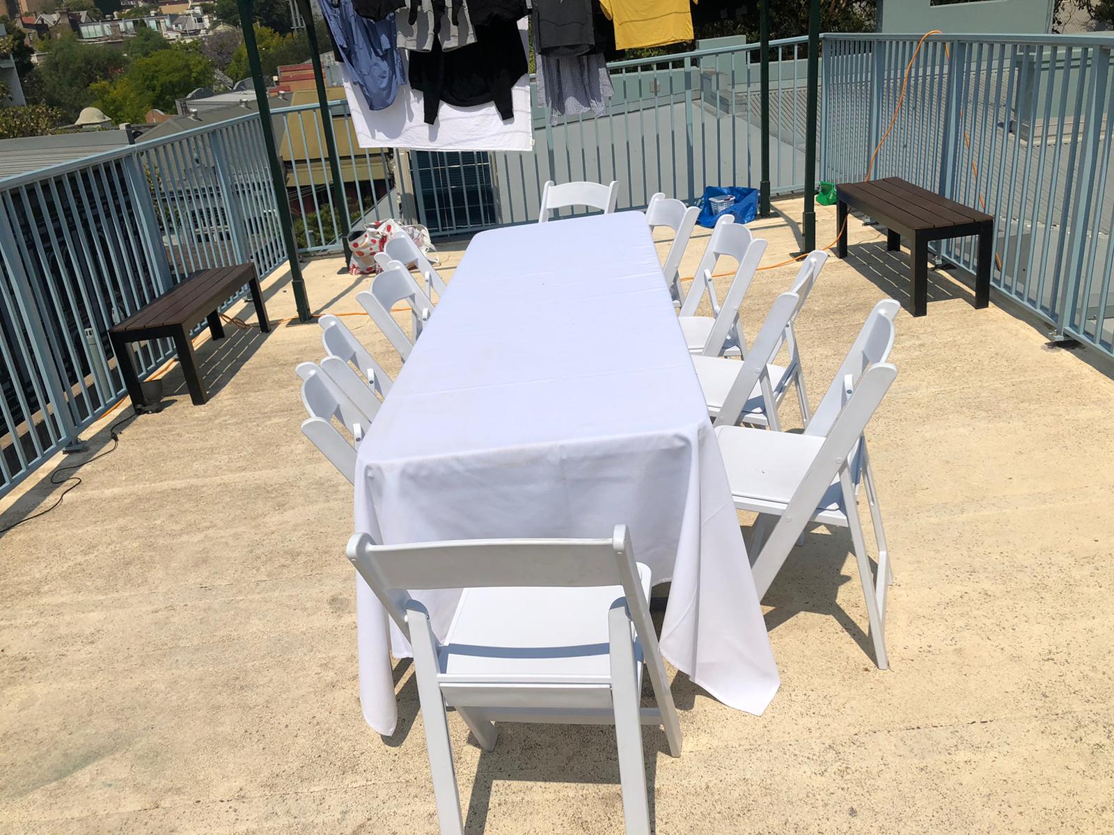 A white plastic table and chairs on a balcony.