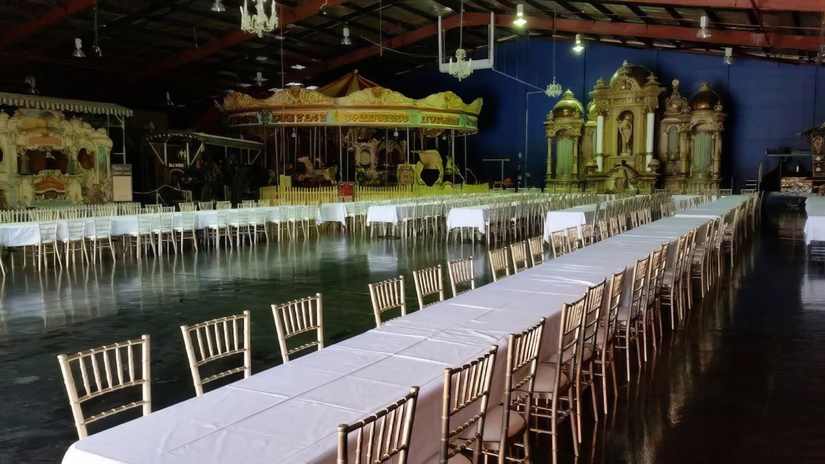 A timber trestle table, measuring 1.8m in length, set up in a large hall with a carousel for hire.