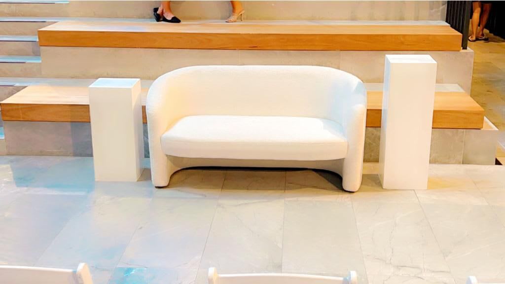 A white chair sits on top of a set of steps available for Bouclé 2 Seater Sofa Lounge Hire.