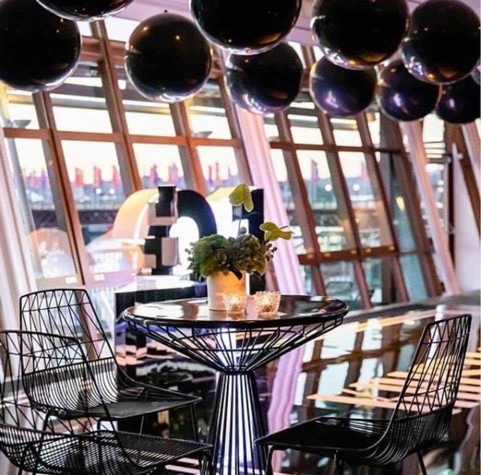 A table with black balloons in the middle of a room, enhanced by a Black Wire Stool.