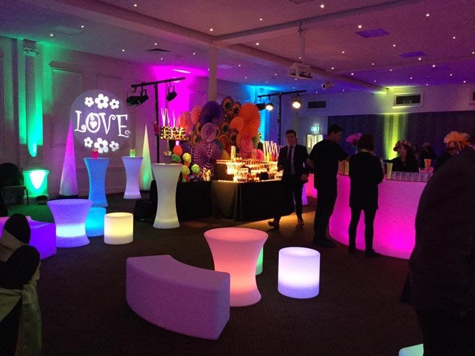 A room filled with Glow Cylinder Seats illuminated by colorful lights.