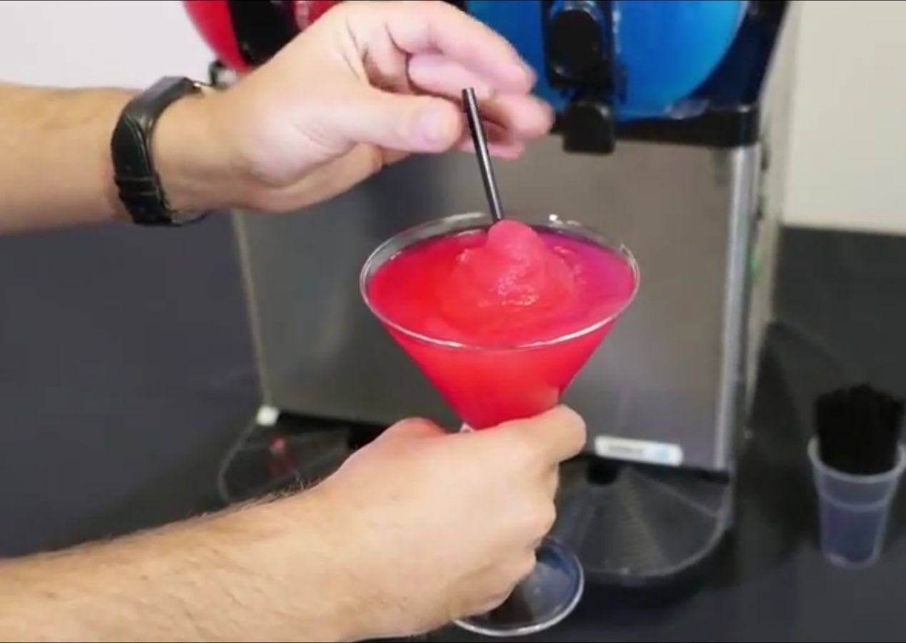 A person pouring *60 drinks* into a machine.