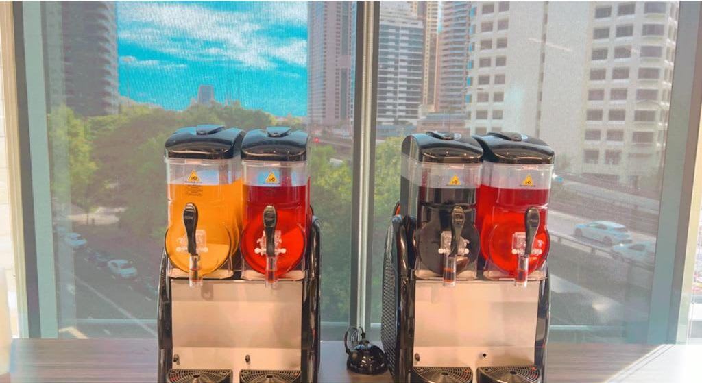 Two Slushie Machines on a table in front of a window, offering a package of 240 Drinks.