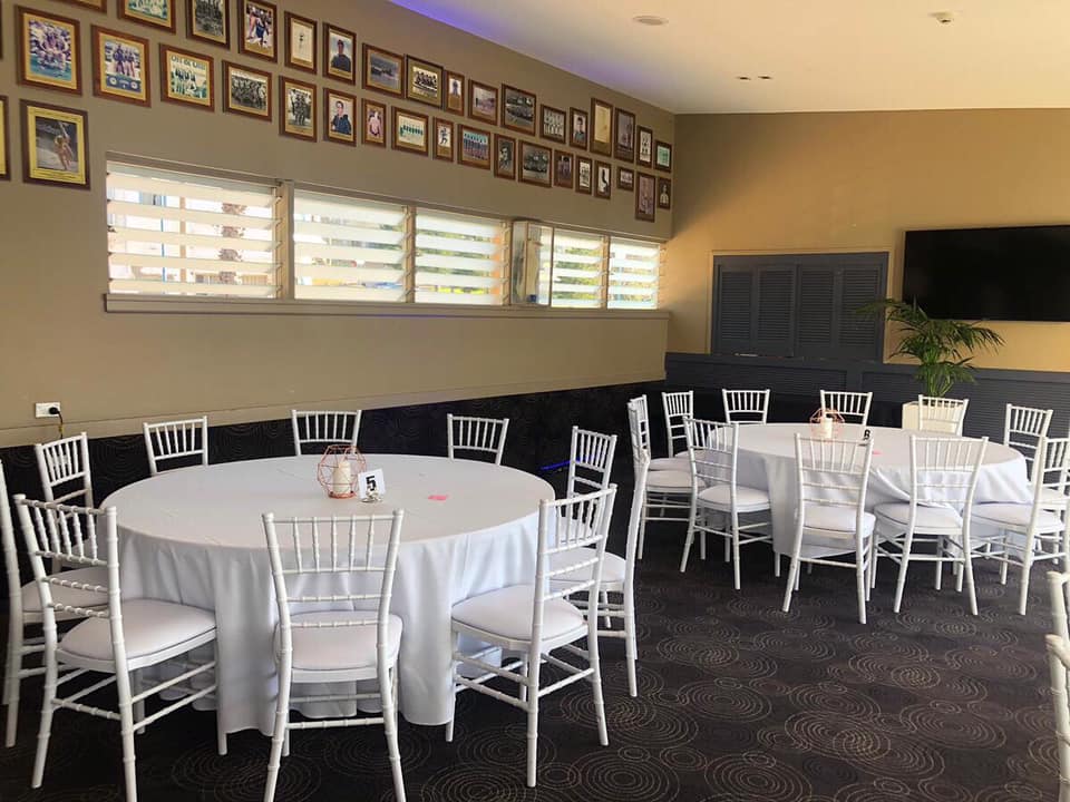 A room with round timber banquet tables and chairs set up for a party.