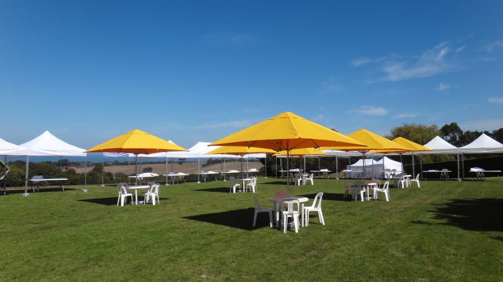 A group of tables and chairs on a grassy field with yellow umbrellas, enhanced by the addition of a 3mx3m Pop Up Marquee With White Roof.