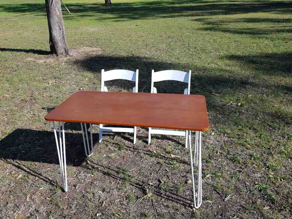 Two chairs and a table for hire in the grass.