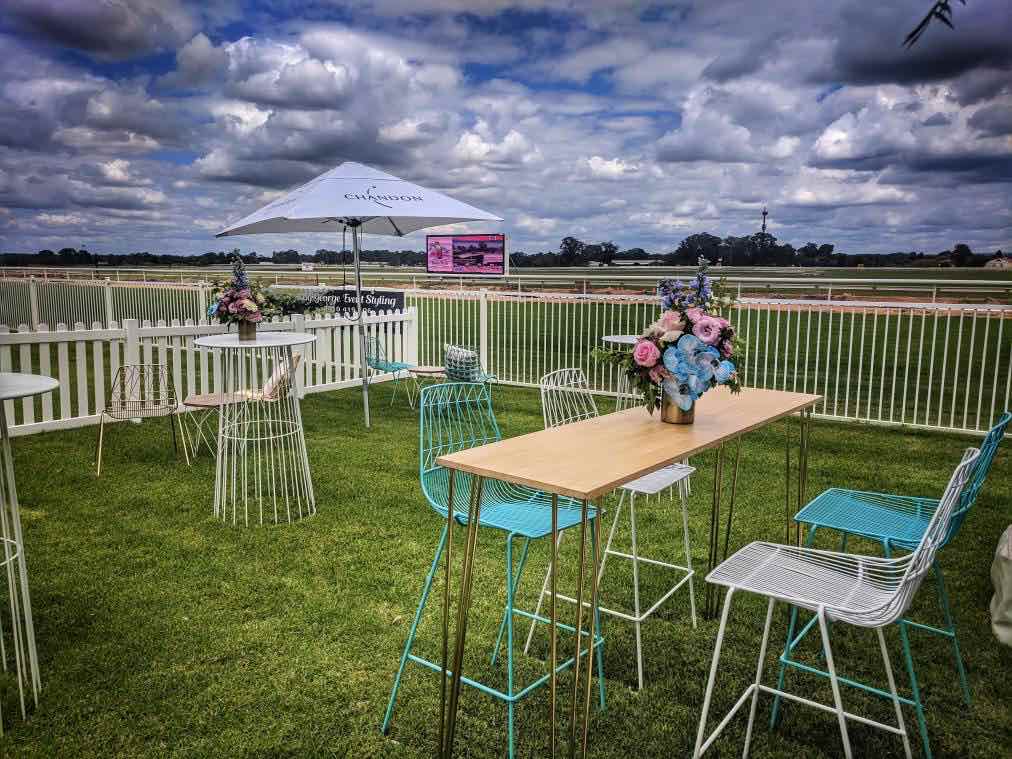 Turquoise blue chairs are set up on a grassy field along with a table.