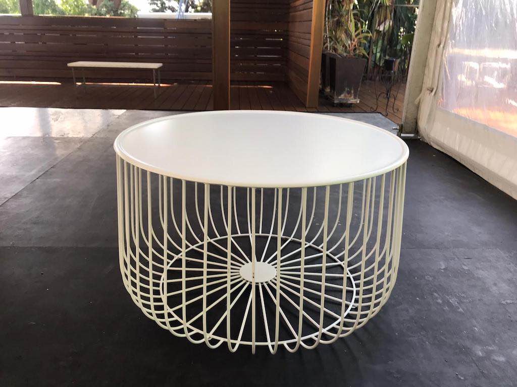 A white wire coffee table with a basket on top.