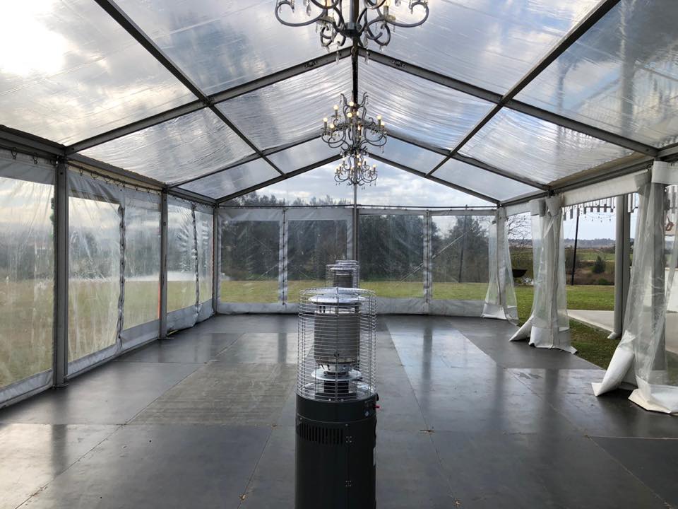 A clear tent with a chandelier hanging in the middle, perfect for luxurious events in framed marquees.