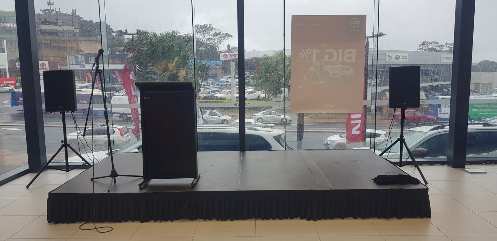 A stage with speakers and a lectern in front of a window.