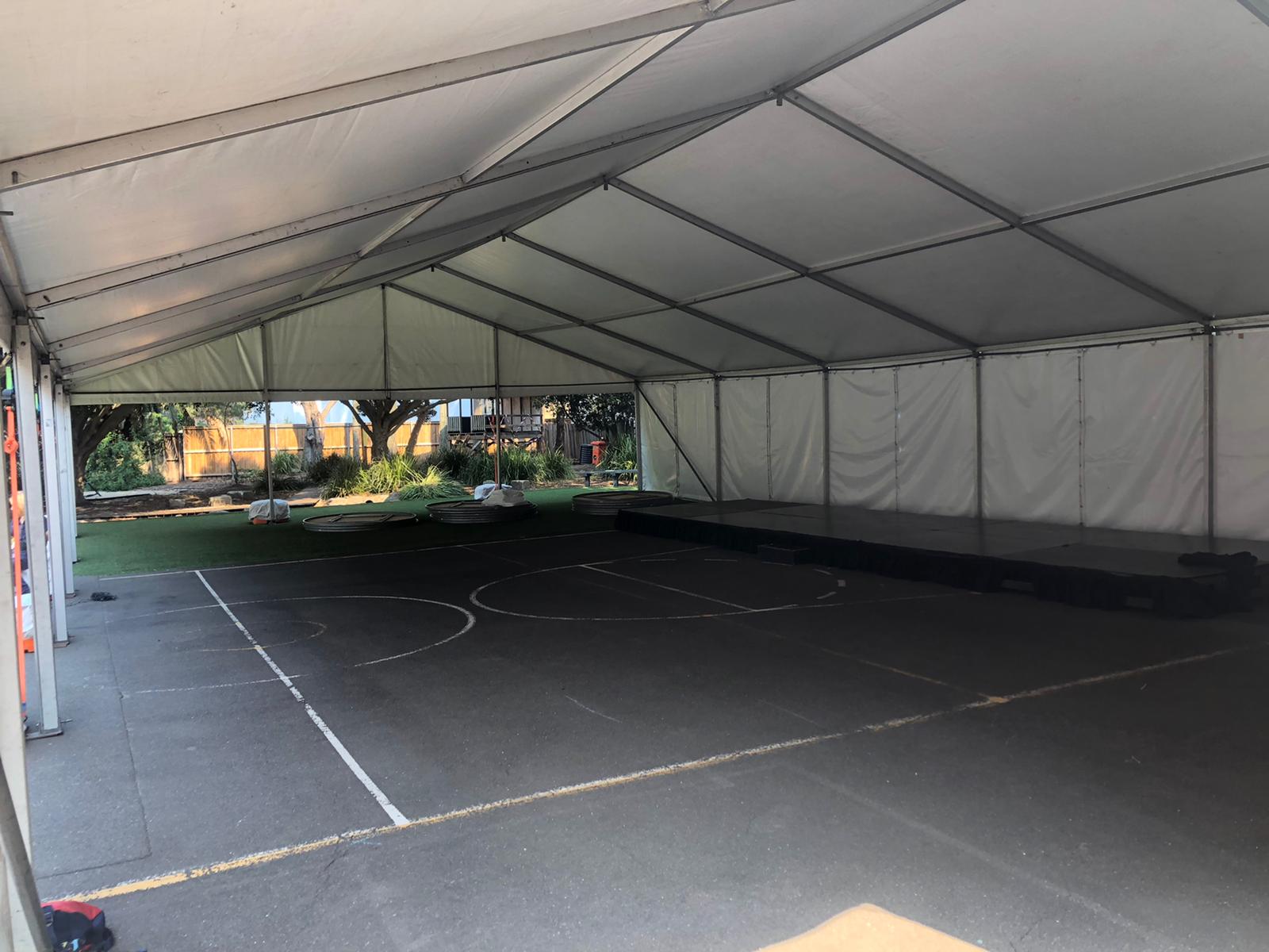 A framed marquee, measuring 6m x 6m, transformed into a white tent with a basketball court inside.