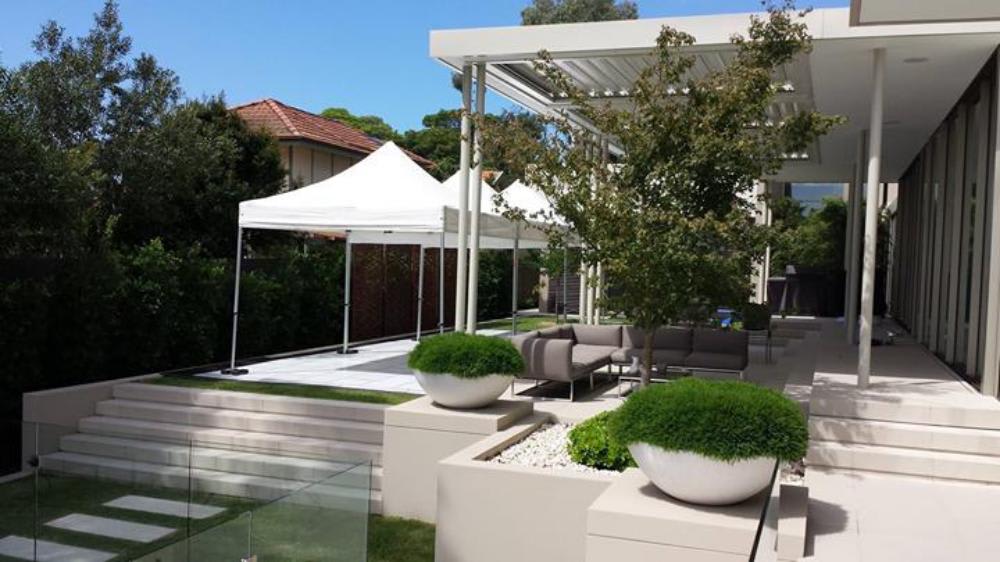 A modern backyard with a white 3mx3m pop-up marquee tent and potted plants.