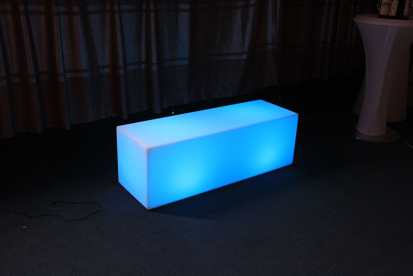 A blue LED cube sitting on top of a carpet, emitting a mesmerizing glow.