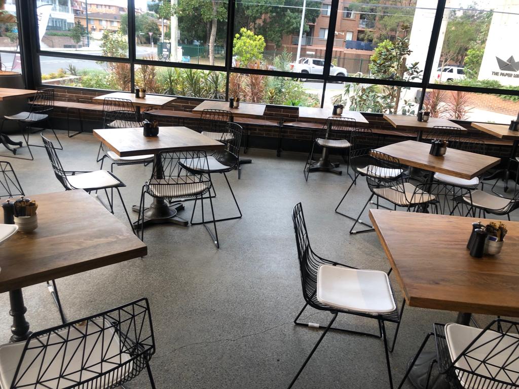 An empty restaurant with Black Wire Chairs and tables.