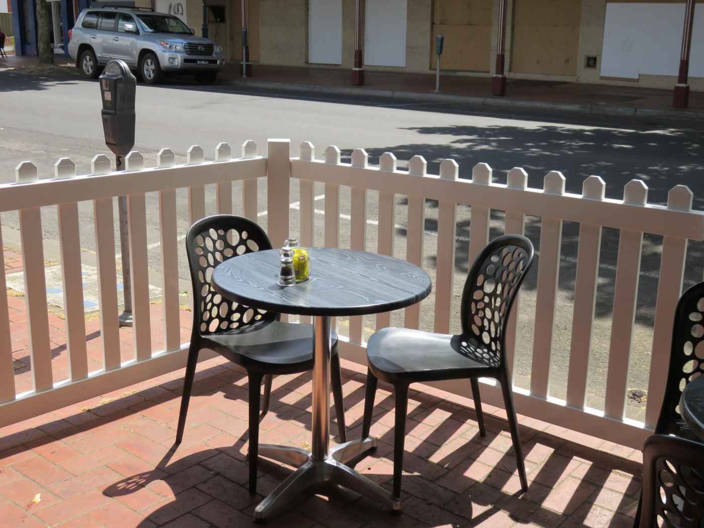 A table and chairs on a balcony with a white picket fence.