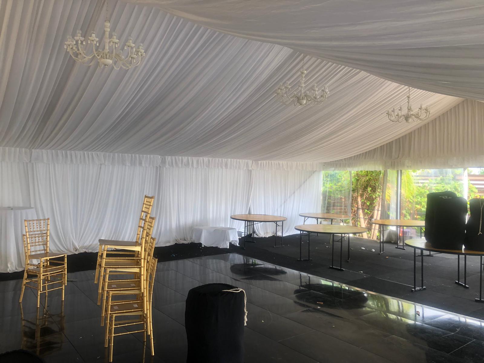 A white framed marquee with gold chairs and tables.