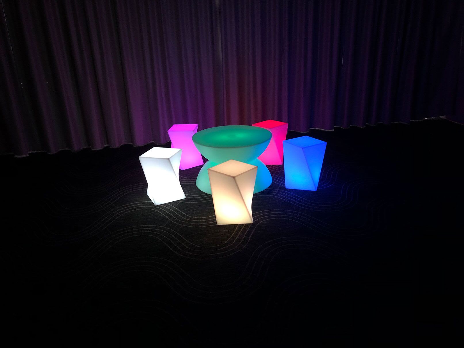 A group of vibrant stools in front of a curtain, available for hire.