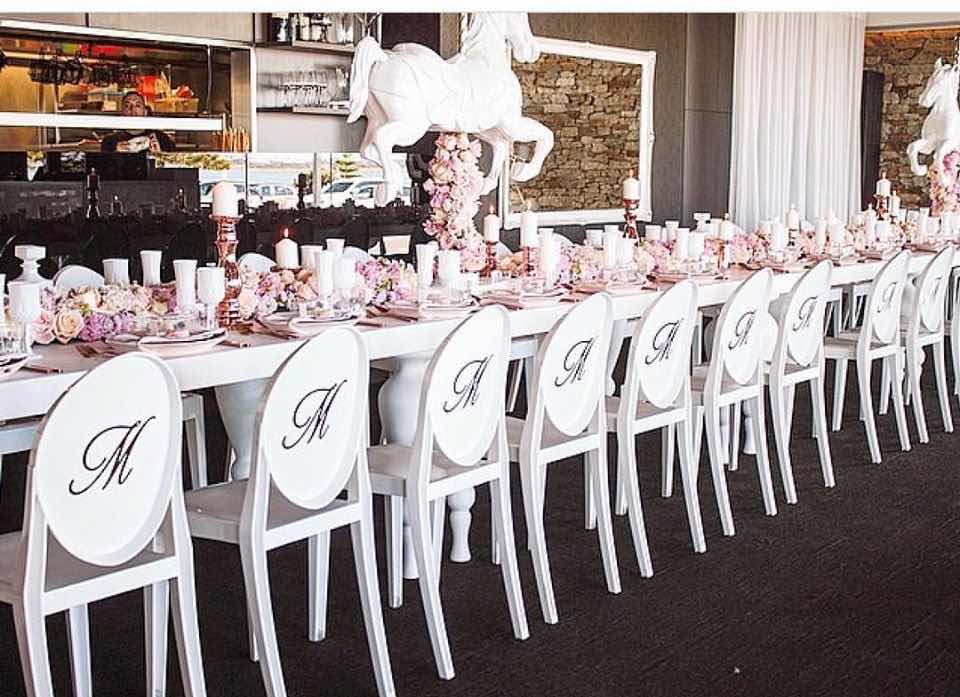 A table set up with white Victorian chairs and a white tablecloth.