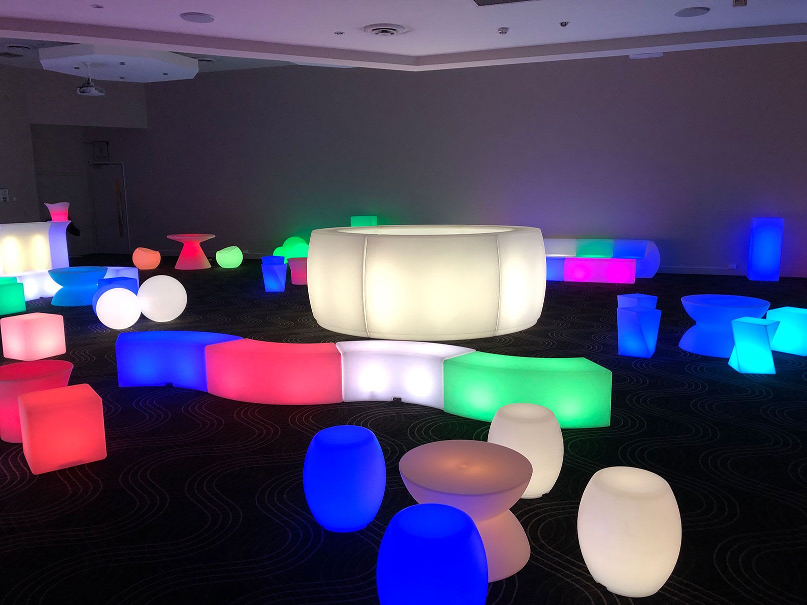 A room full of colorful glow stools and tables for hire.