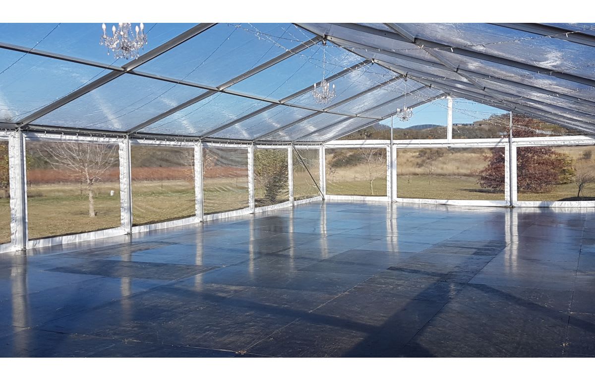 A spacious framed marquee with a stunning glass floor and elegant chandeliers.