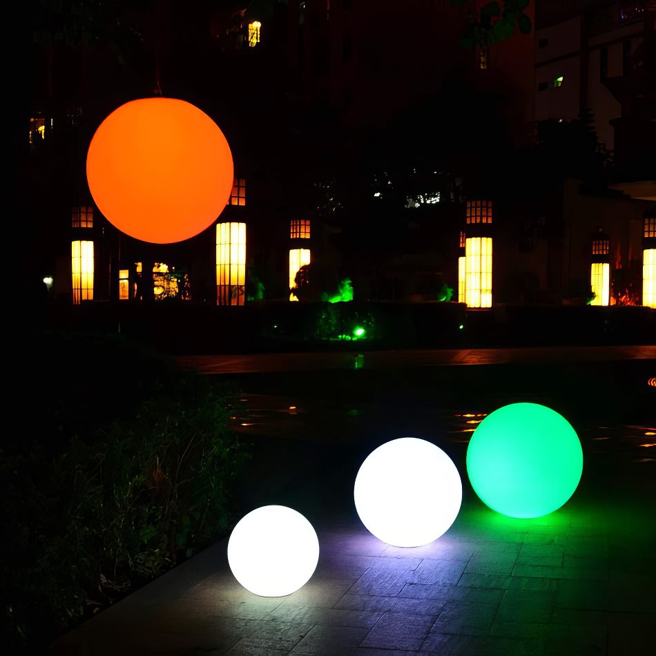 A group of glowing lighted balls in a park at night, available for Glow Sphere Hire.