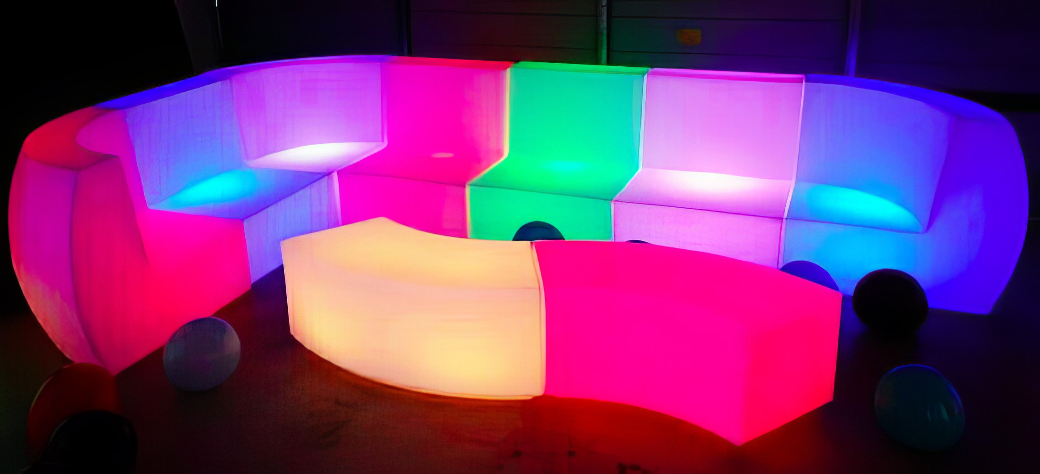 A Glow Lounge Suite Hire in a dark room set with colorful LED sofas.