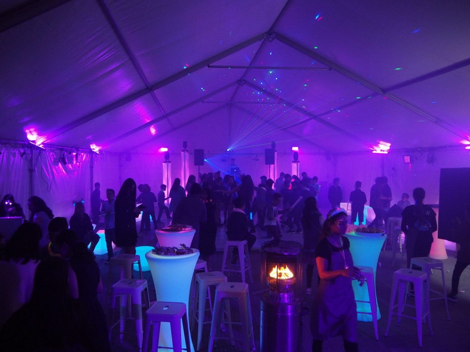 A group of people in an 8m x 21m - Framed Marquee with purple lights.