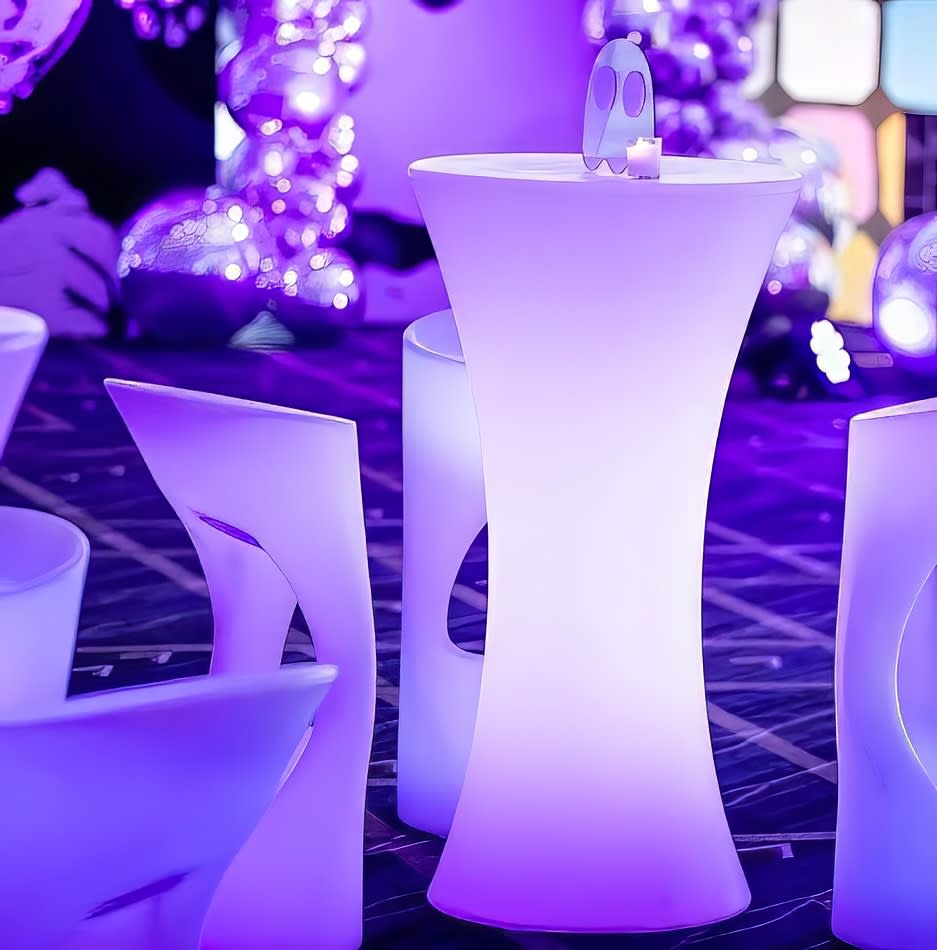 A group of purple glow stools and tables in a party setting.