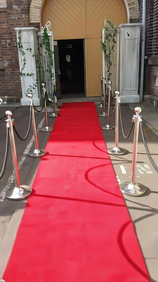 A red carpet leading up to a doorway, with chrome bollards hire adding an elegant touch.