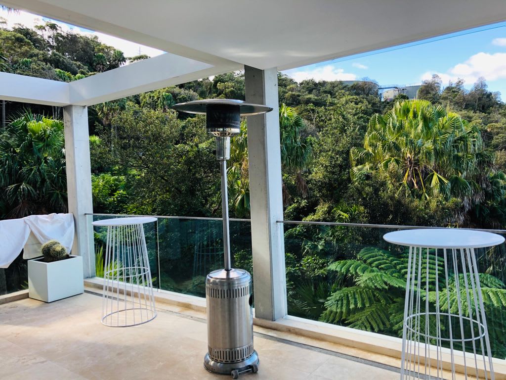 A balcony with a table and chairs and a Mushroom Heater.