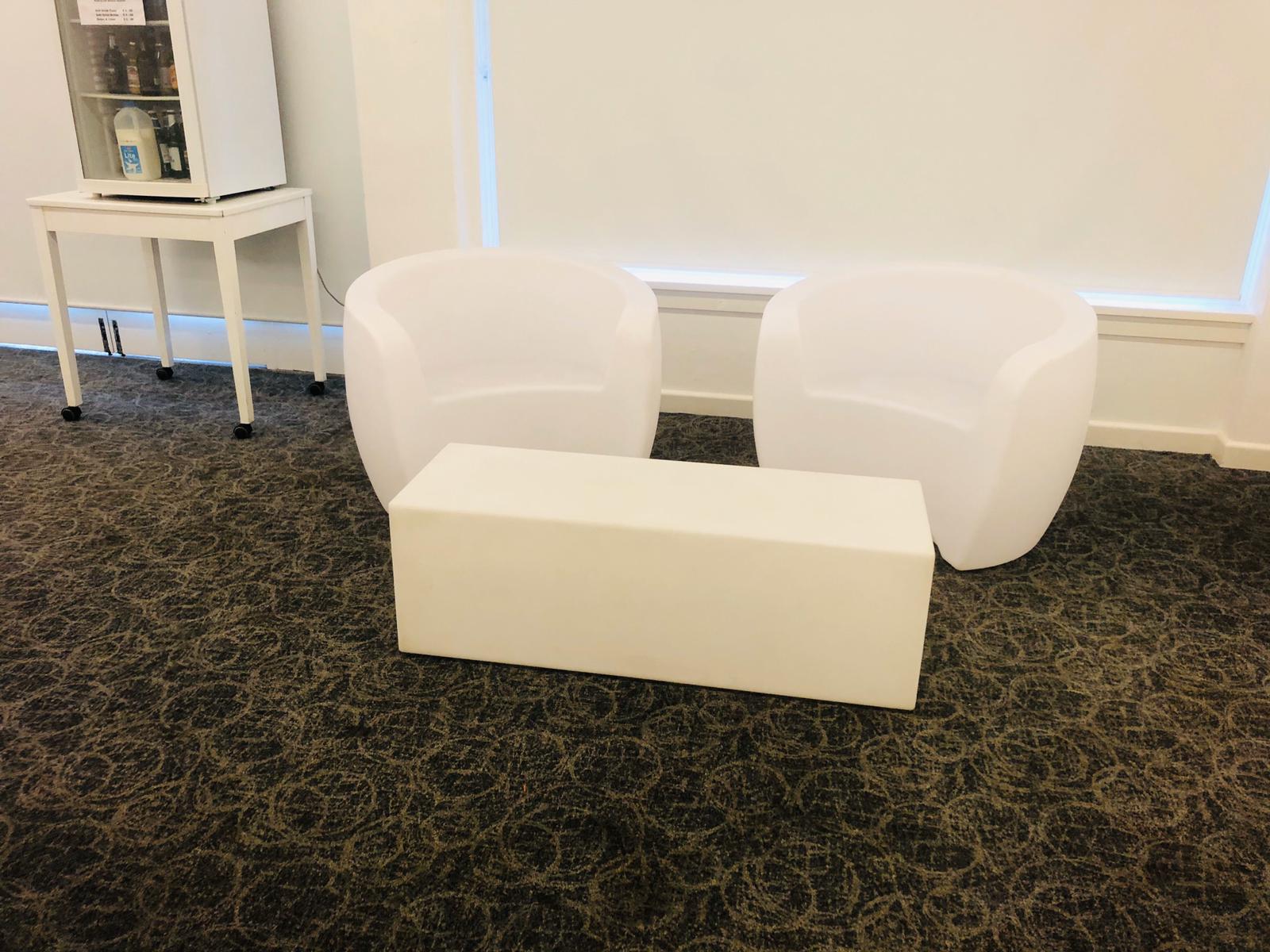 Two white chairs and a glowing table in a room.