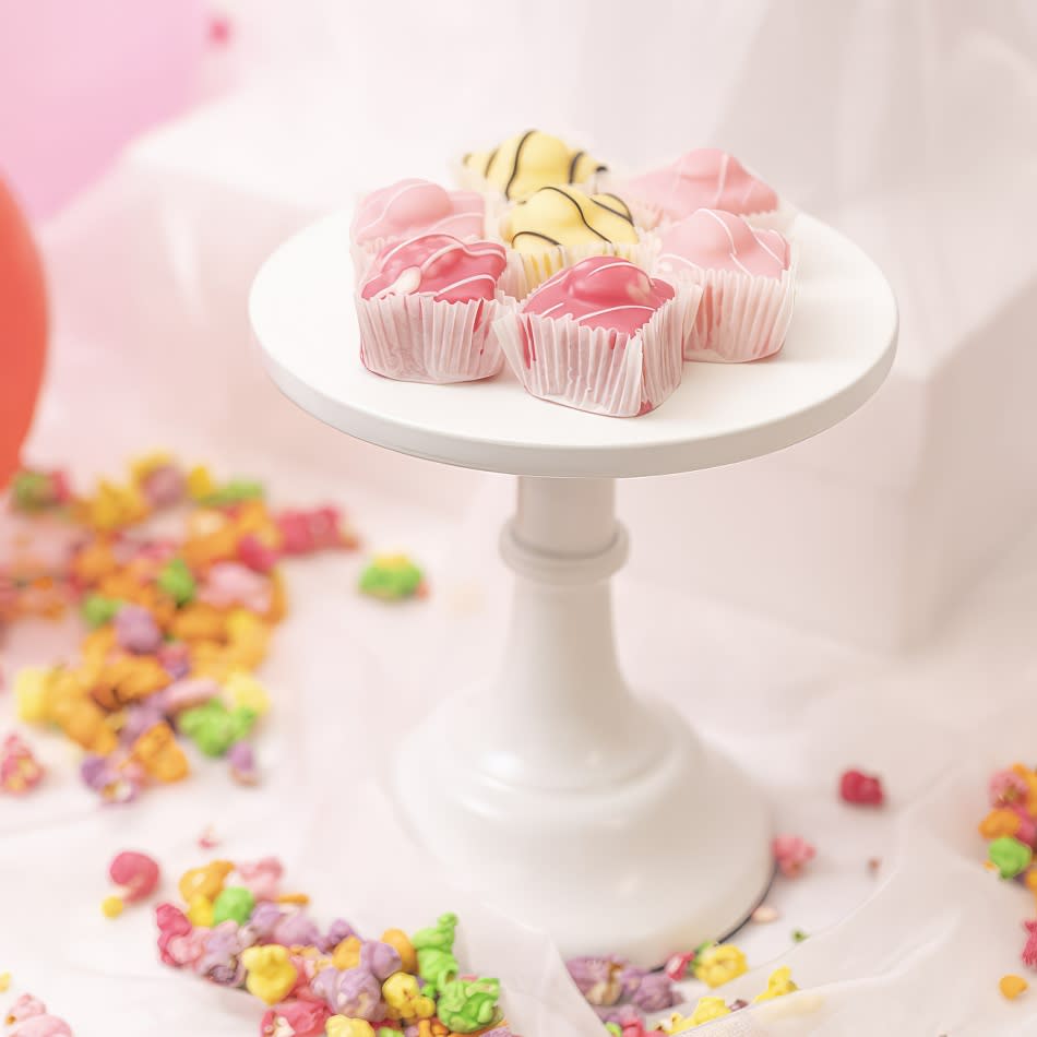 Cupcakes on a white plate with confetti sprinkles displayed on a small cake stand.