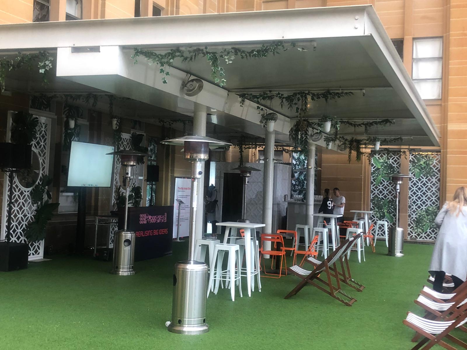 A large outdoor area with tables, chairs, and 3 x Mushroom Heaters w/ Gas Bottles.