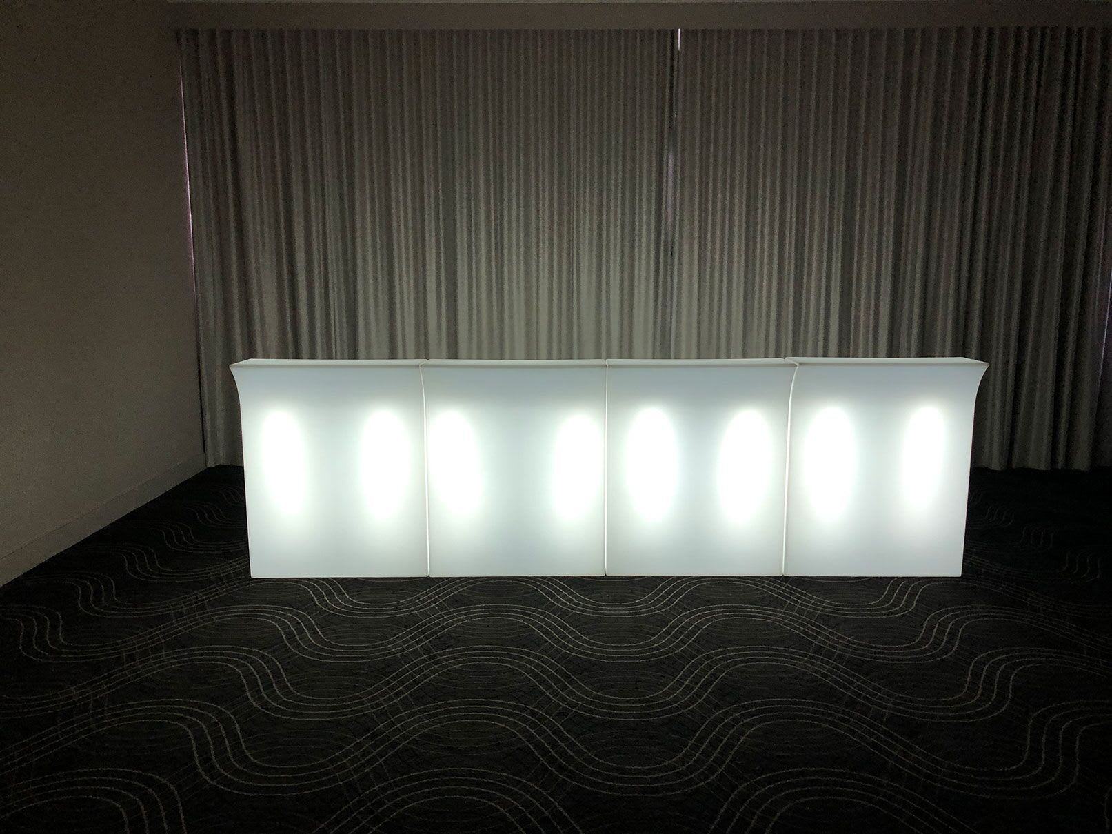 A straight white LED bar in a room with curtains, designed to glow.