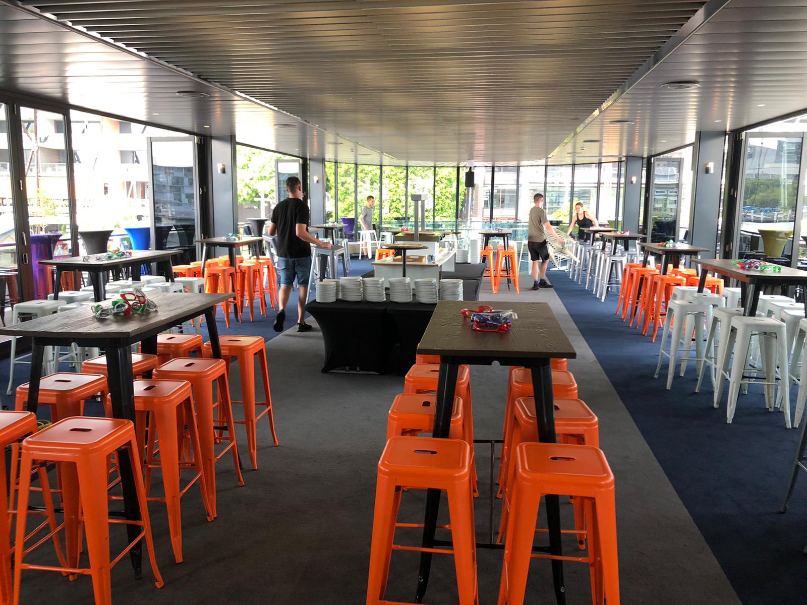 A room full of orange Tolix stools for hire.