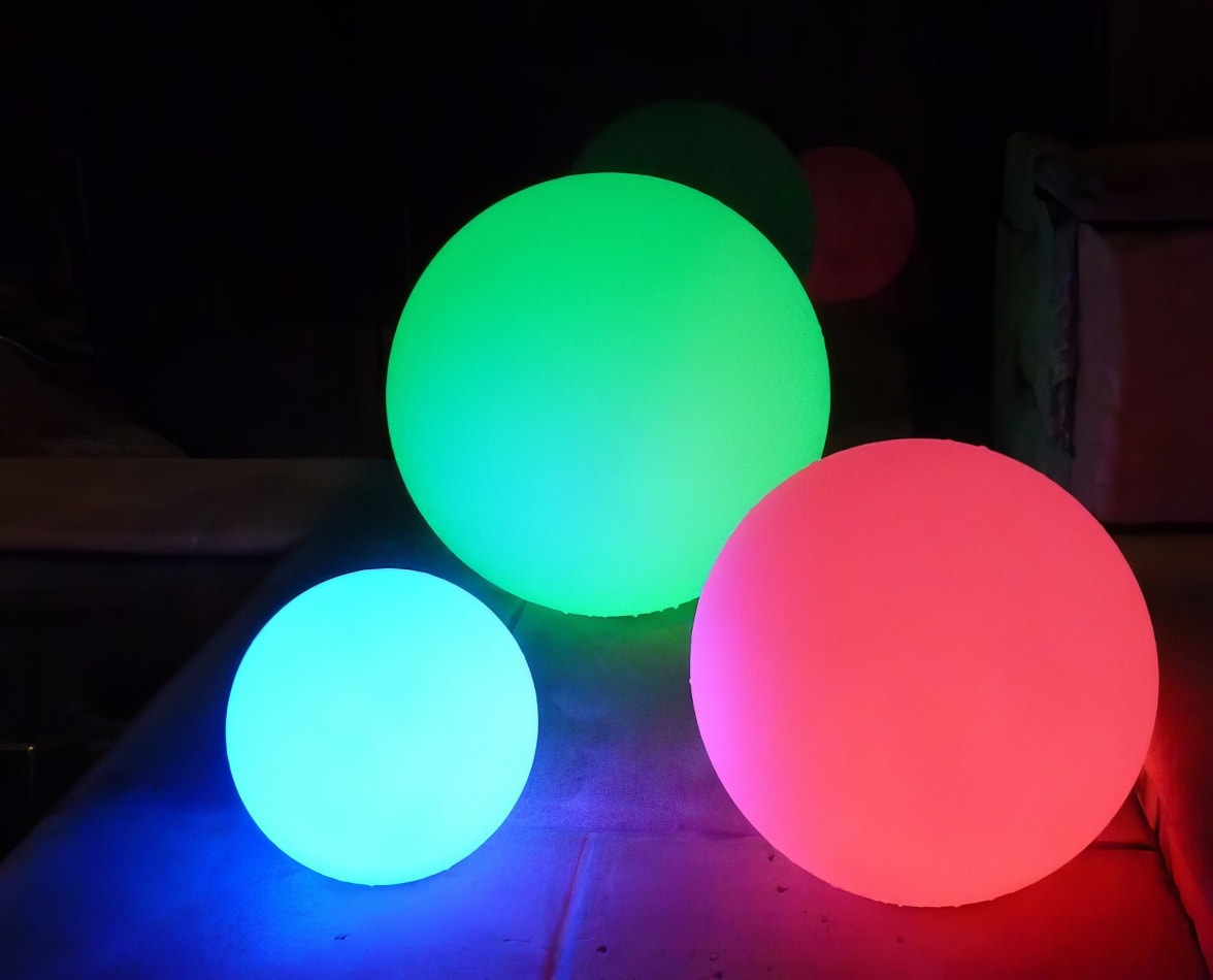 A group of colorful 40cm lighted balls on a concrete floor.