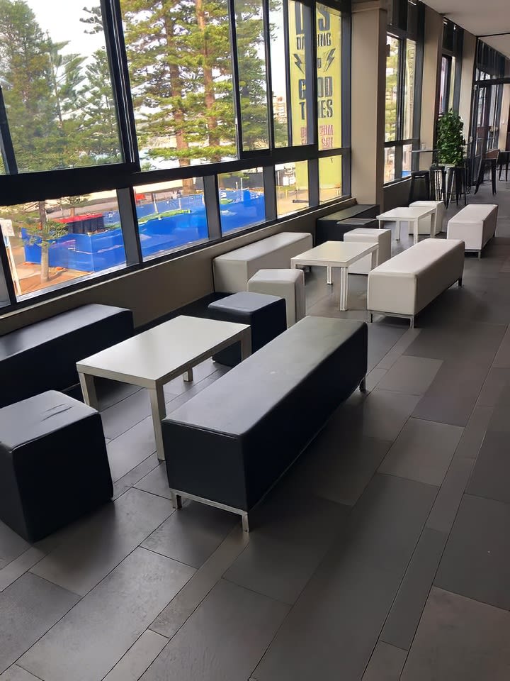 A group of black benches in a room with large windows.