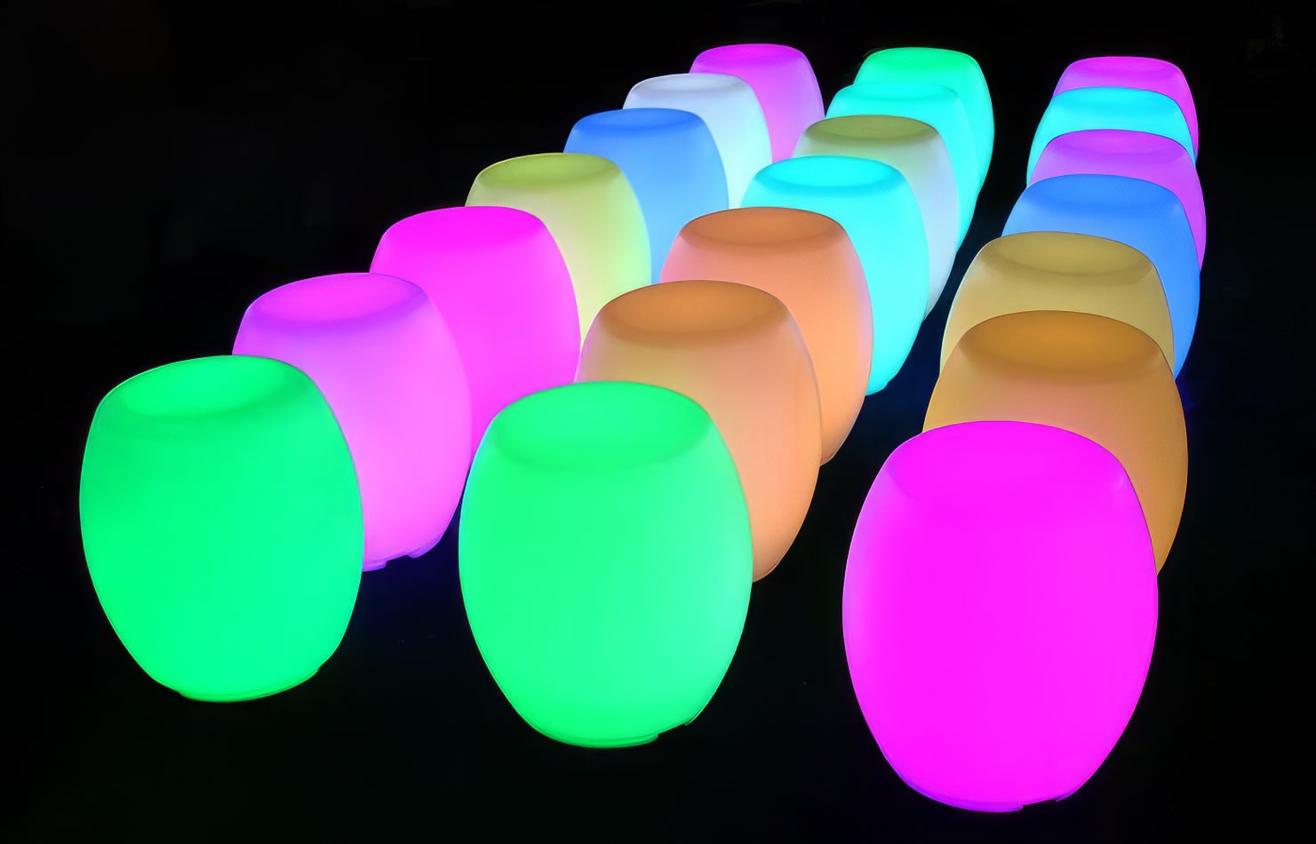 A group of colorful glow stools in a dark room.