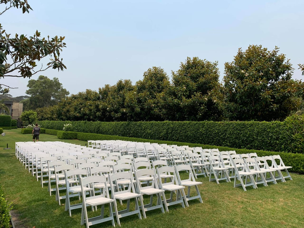 A stunning lawn decorated with white padded folding chairs set up for a beautiful wedding ceremony.