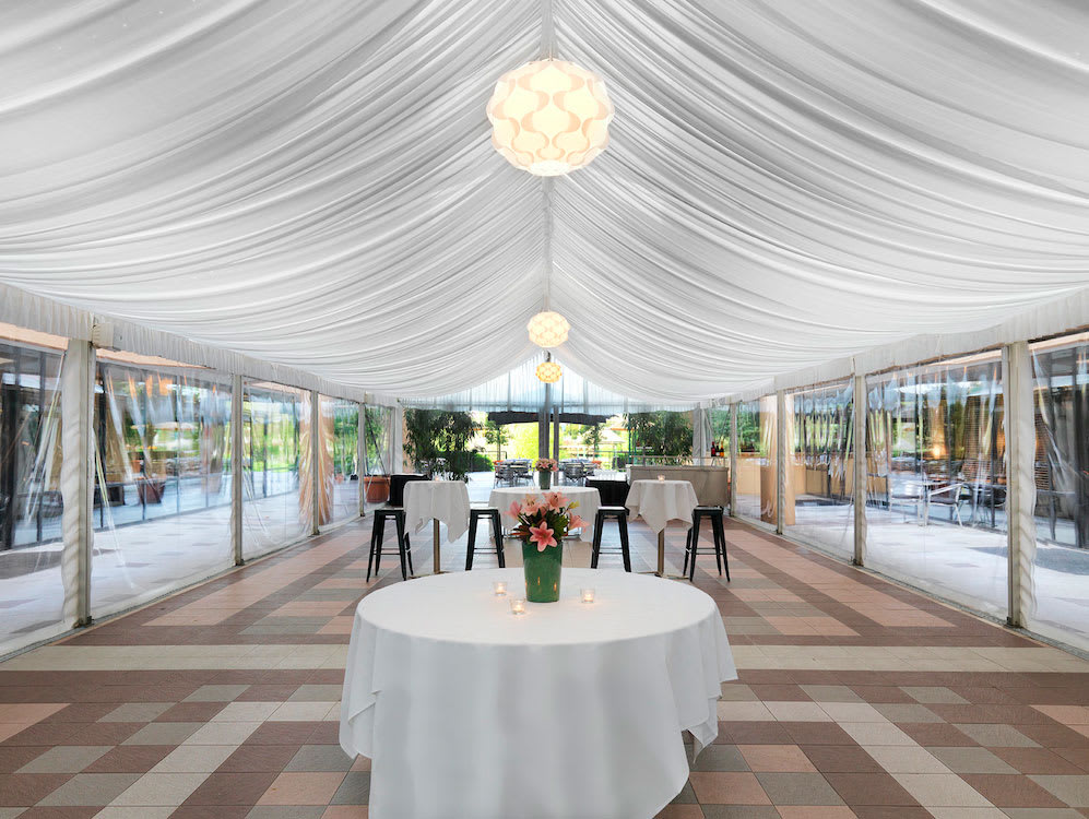 An elegant white tent with a table and chairs, set up inside an 8m x 33m framed marquee.