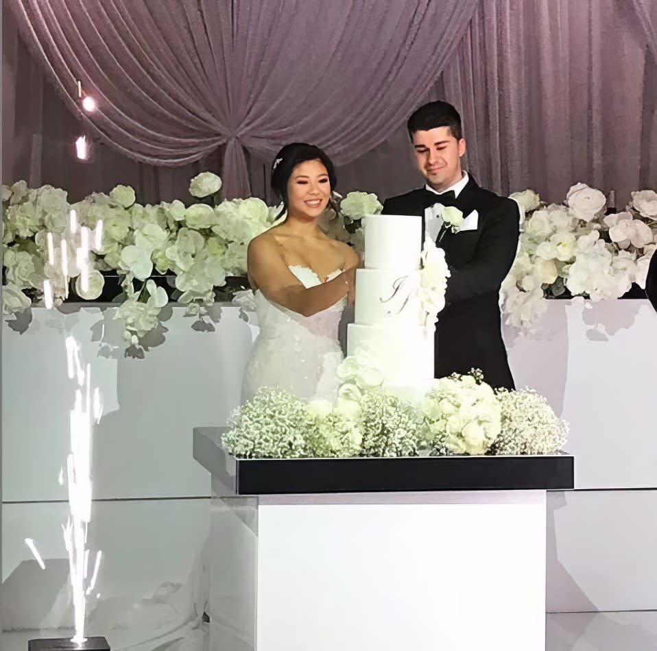 A bride and groom cutting their wedding cake on a beautifully adorned cake table.