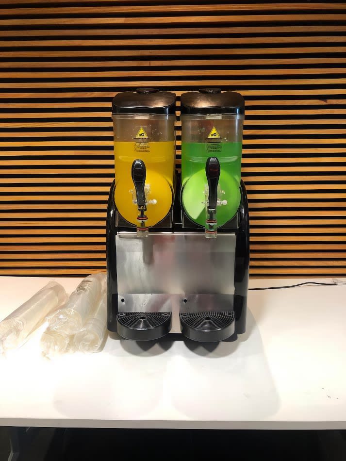 Two juice dispensers on a table next to each other, available for *240 Drinks* with our Slushie Machine Hire: Pkg 3.