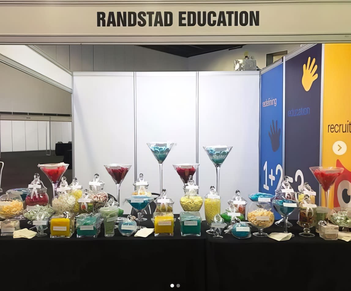 Randstad education showcased their booth at a trade show featuring a black tablecloth for their standard trestle table.