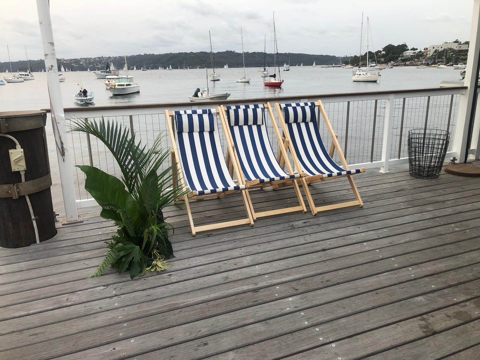 Three deck chairs on a deck overlooking the water hired from Party Hire Group