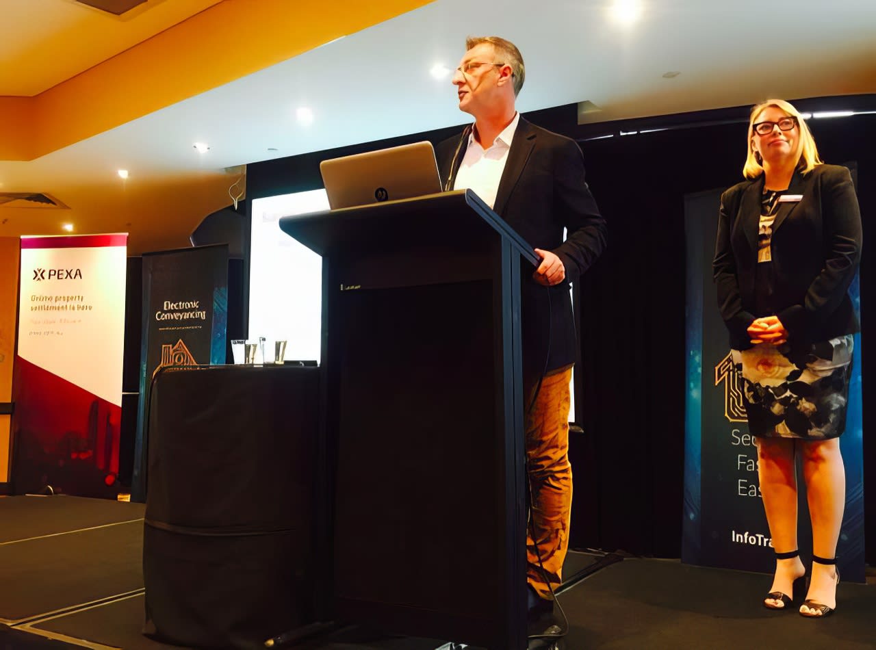 Two people standing at a lectern at an event.