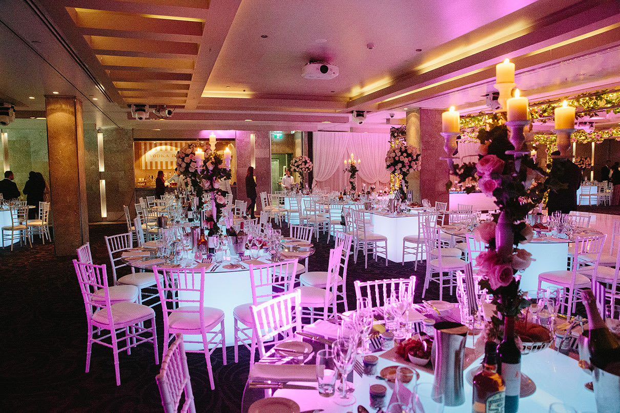 A large room with round glow banquet tables and chairs set up for a wedding.