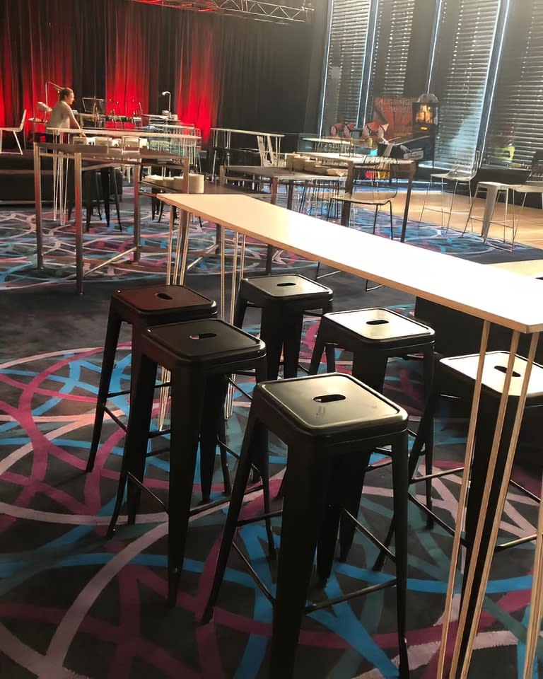 A room with White hairpin High Bar Tables and stools in it.