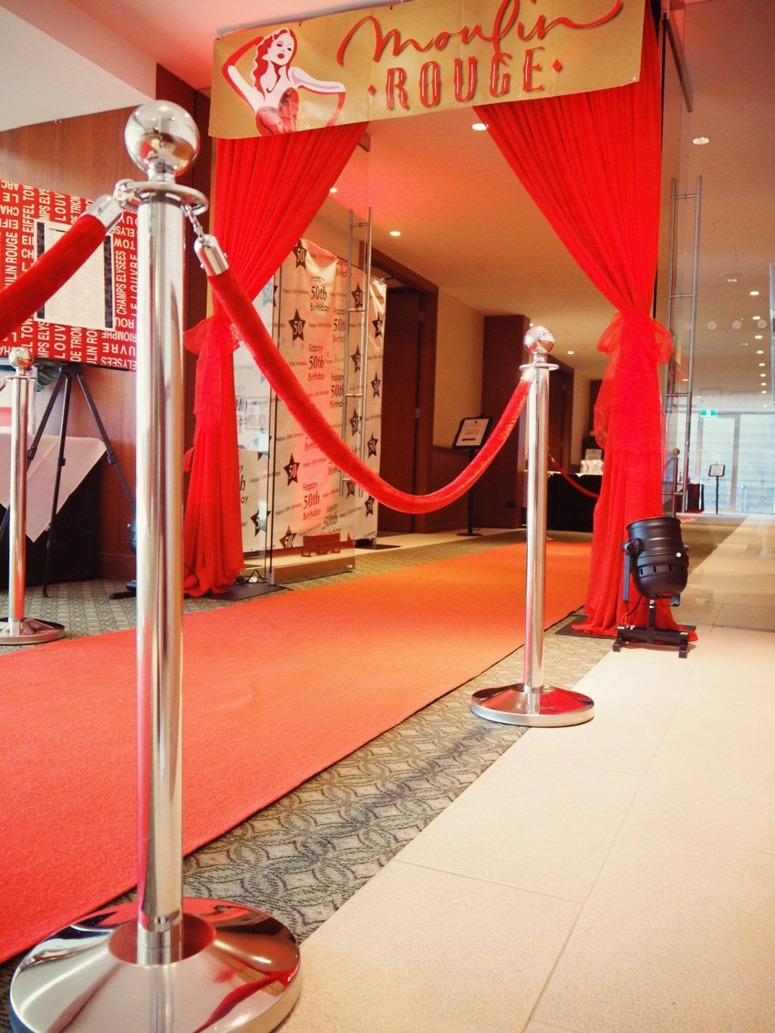 A red carpet with chrome bollards and red ropes.