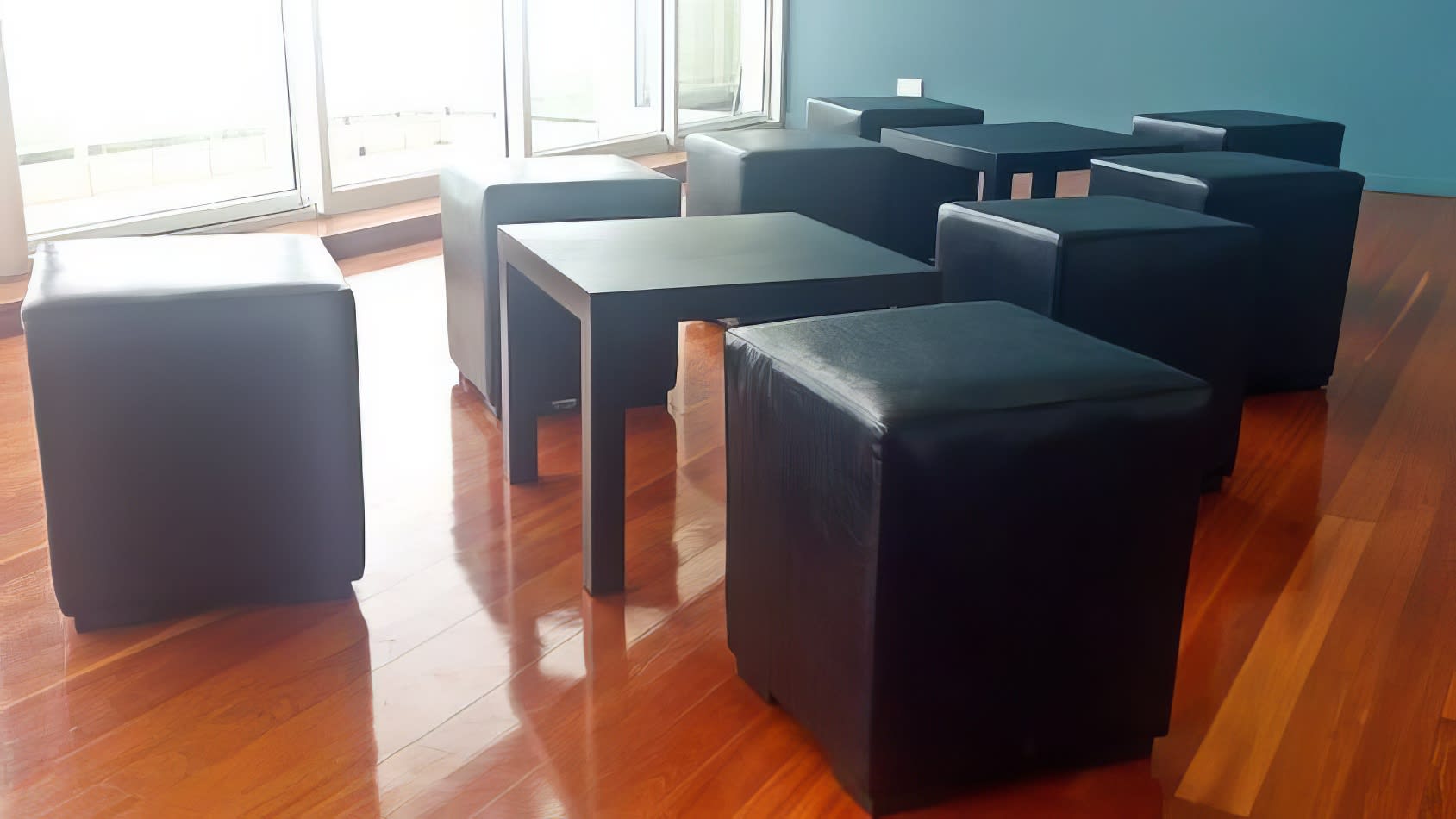 A group of black ottomans on a wooden floor.