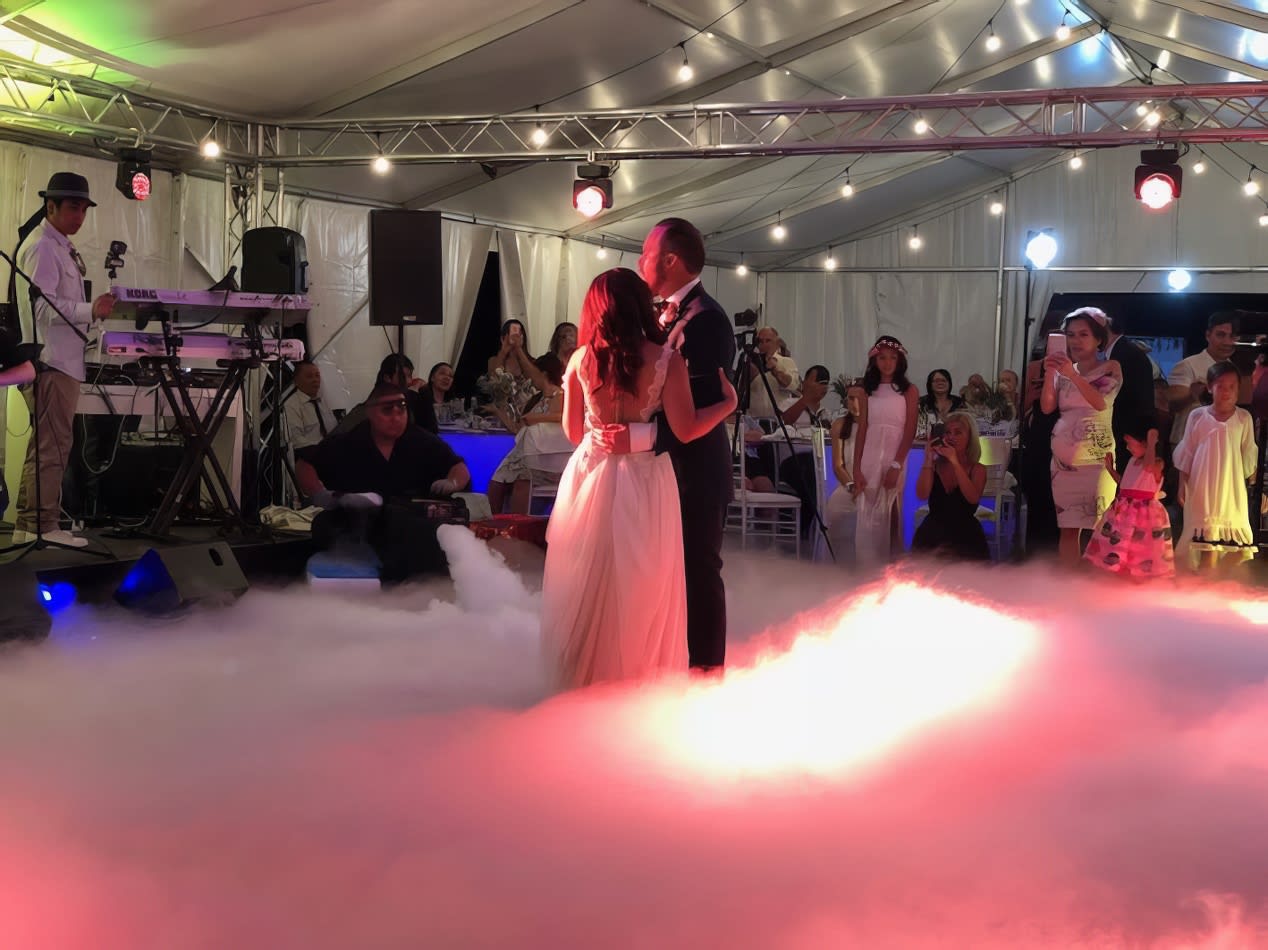 A bride and groom gracefully dancing on a cloud of smoke created by a professional dry ice machine operator.